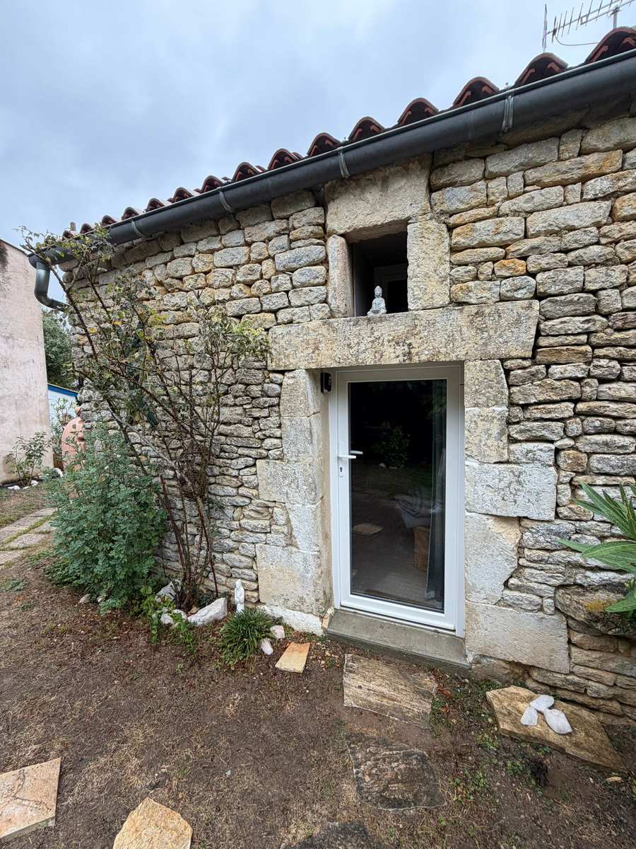 L'entrée vitrée du Studio Zen, ouverte dans le mur en pierre de l'Éco-Hameau SOI à Liez