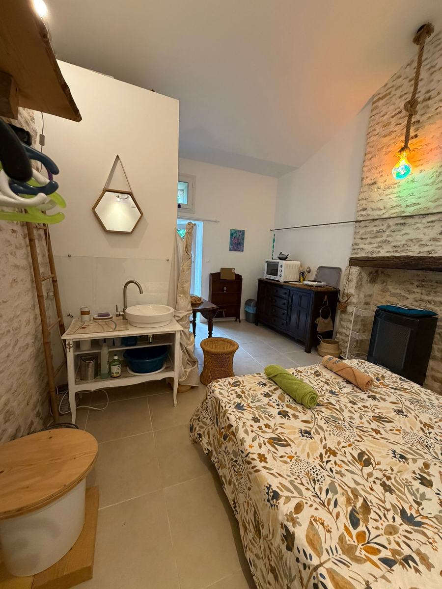 Vue d'ensemble du Studio Zen à Liez : le lit, le coin lavabo, les toilettes sèches et le coin cuisine sous la charpente